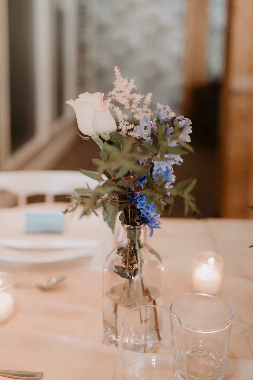 Delicate bud vase with garden rose and blue delphinium